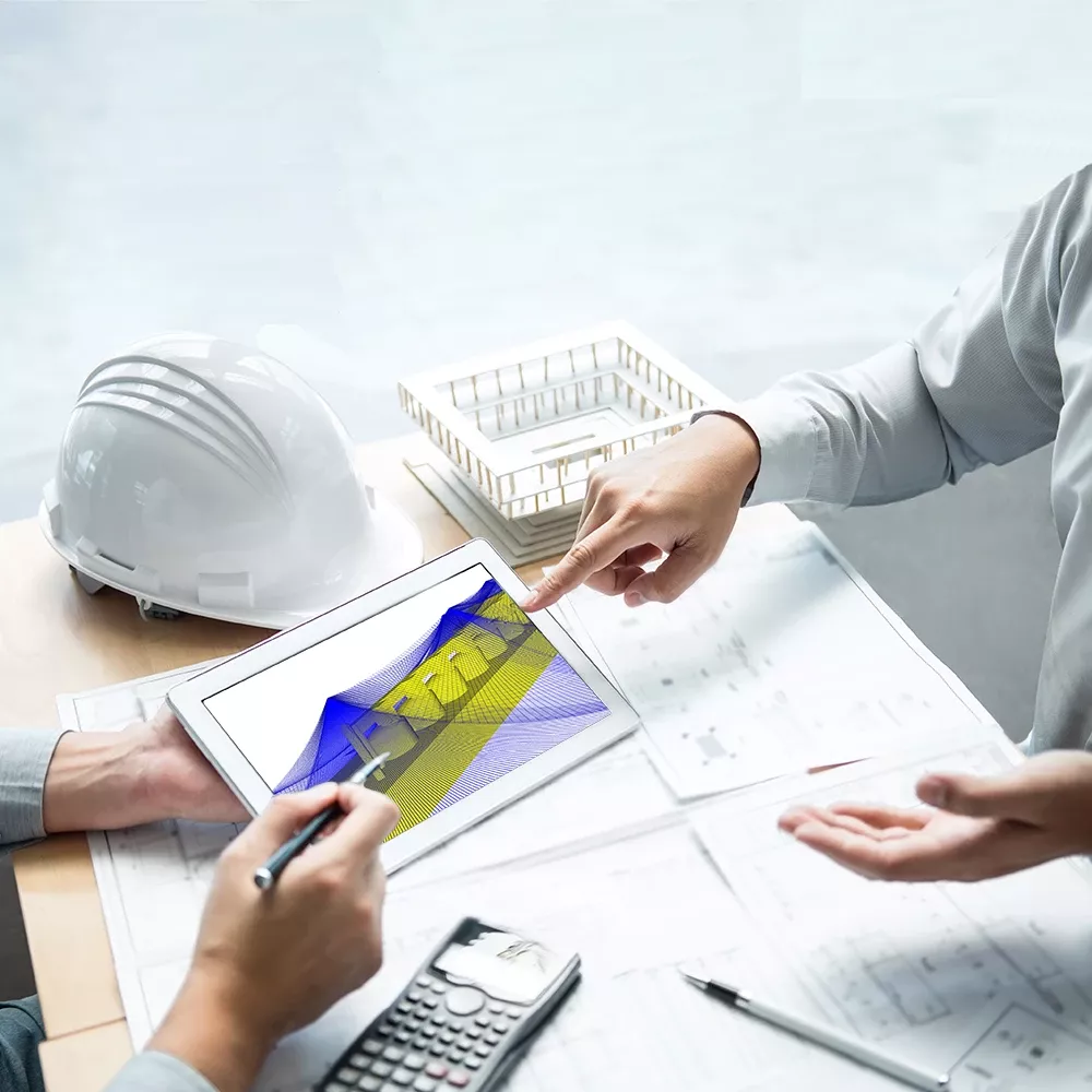 Ein Schreibtisch voller technischer Unterlagen und ein Tablett. Finger deuten darauf. 