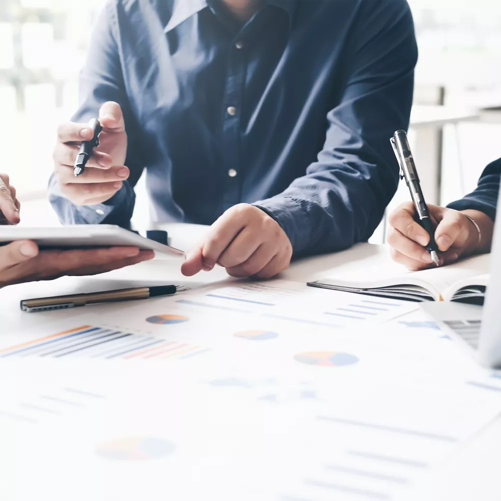 Geschäftsleute arbeiten zusammen, prüfen Daten auf einem Tablet und Dokumente.