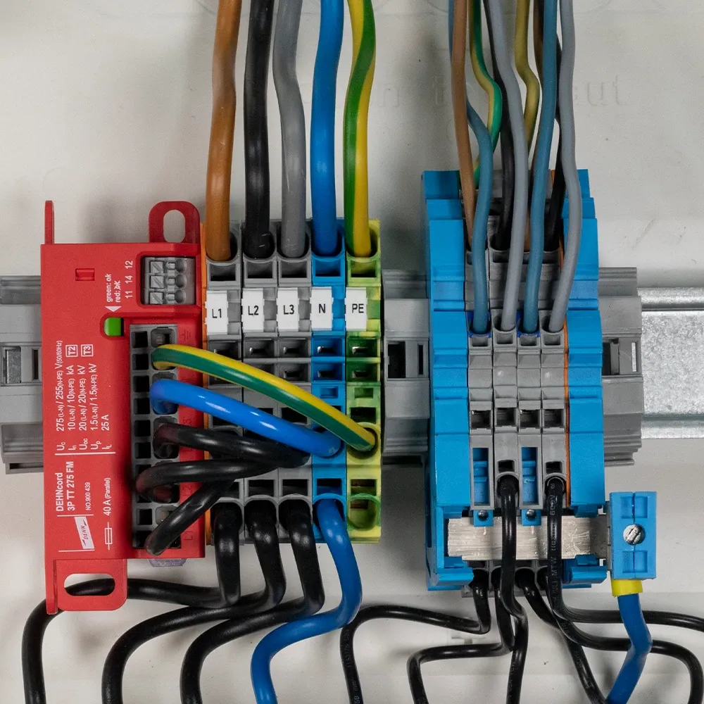 Alt text (EN, ≤125 characters): Surge protection device with L1, L2, L3, N and PE terminals wired inside electrical distribution board