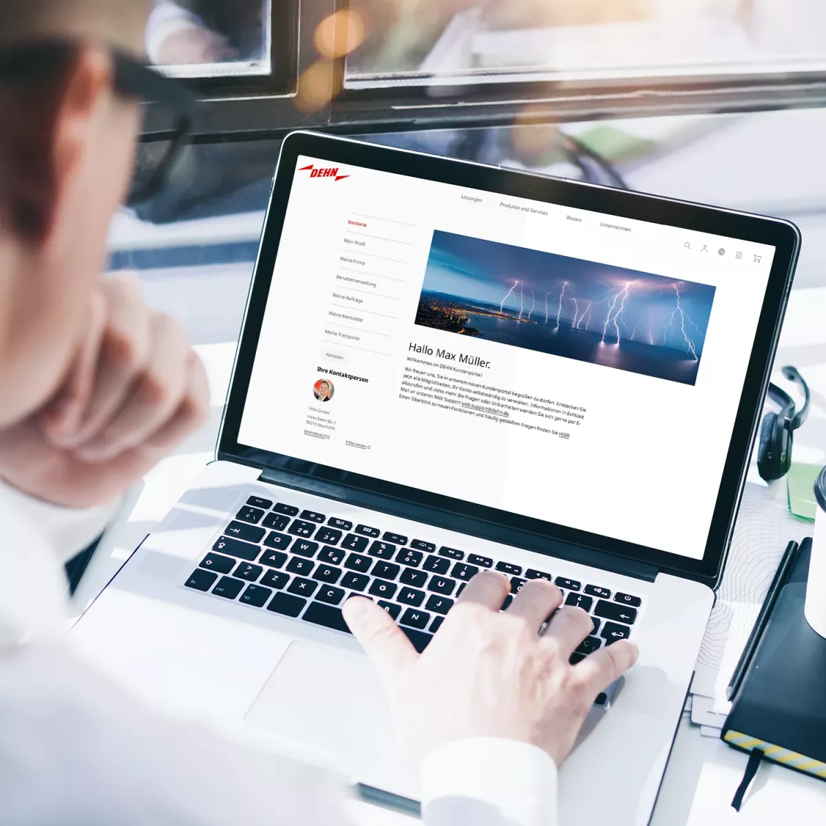A person using a laptop, viewing a webpage featuring a profile and a header image of wind turbines against a cloudy sky.